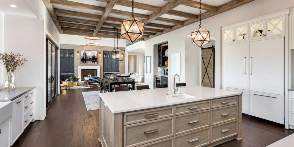 Beautiful modern kitchen with island and wood beamed cieling with view to family room with fireplace