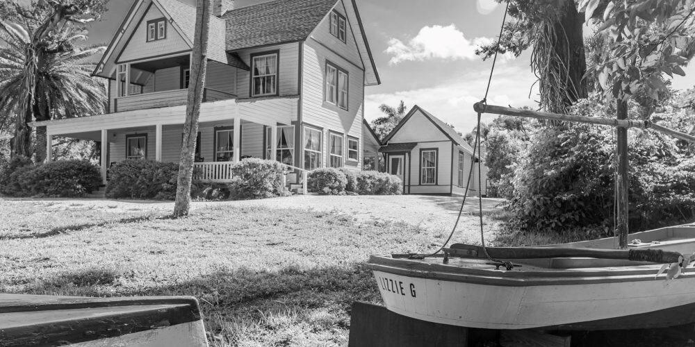 black and white photo of historic house and small wooden boats in foreground
