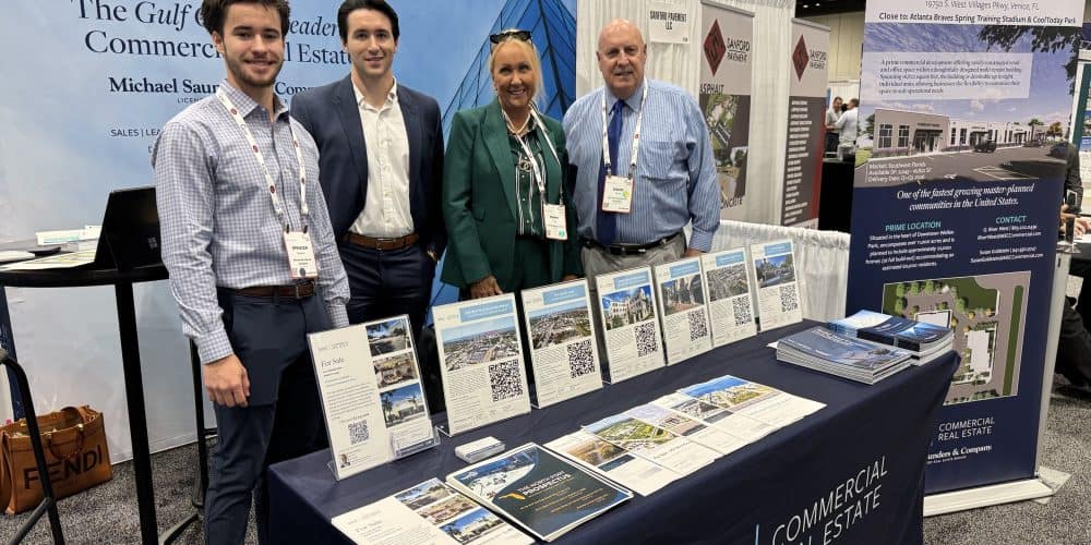 4 people standing in Michael Saunders & Company booth at ICSC event