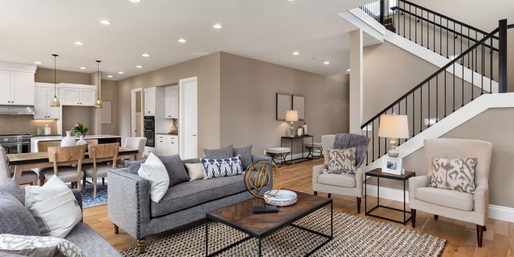 Nice interior shot of a living room with modern neutral furniture and staircase in the back