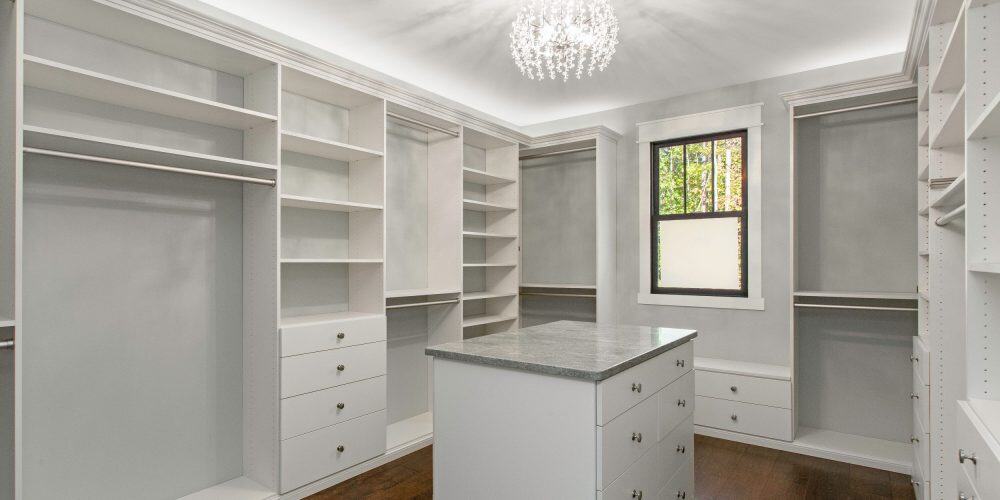 Luxurious Walk-In Closet With White Shelves And Elegant Chandelier - empty showing lots of storage