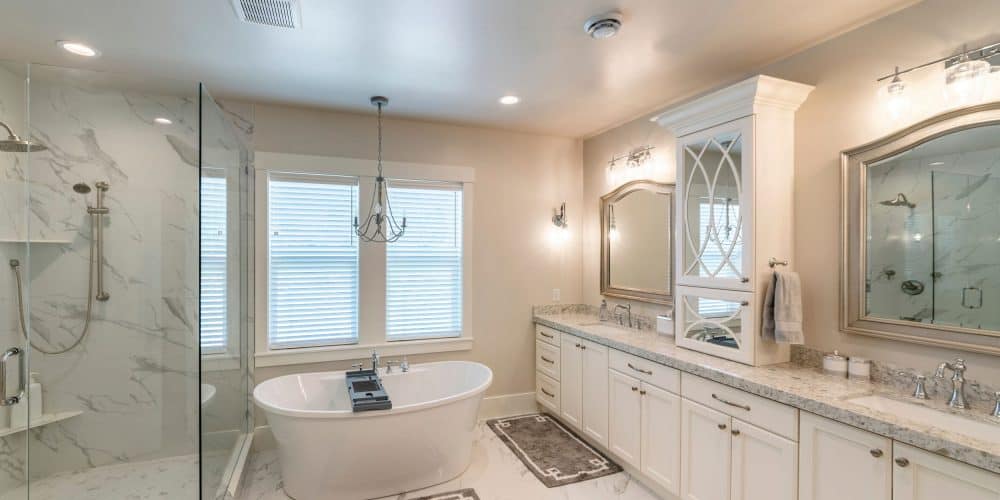 Luxurious master bathroom with marble tiles and window soaking tub and glass walk in shower