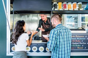 Man at women getting food from a food truck