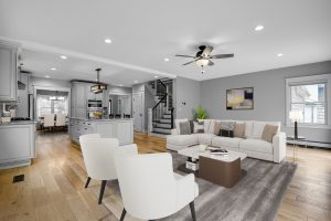 Contemporary interior of home with white chairs, sofa, and wood flooring