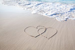 2 interlinking hearts drawn on the sand