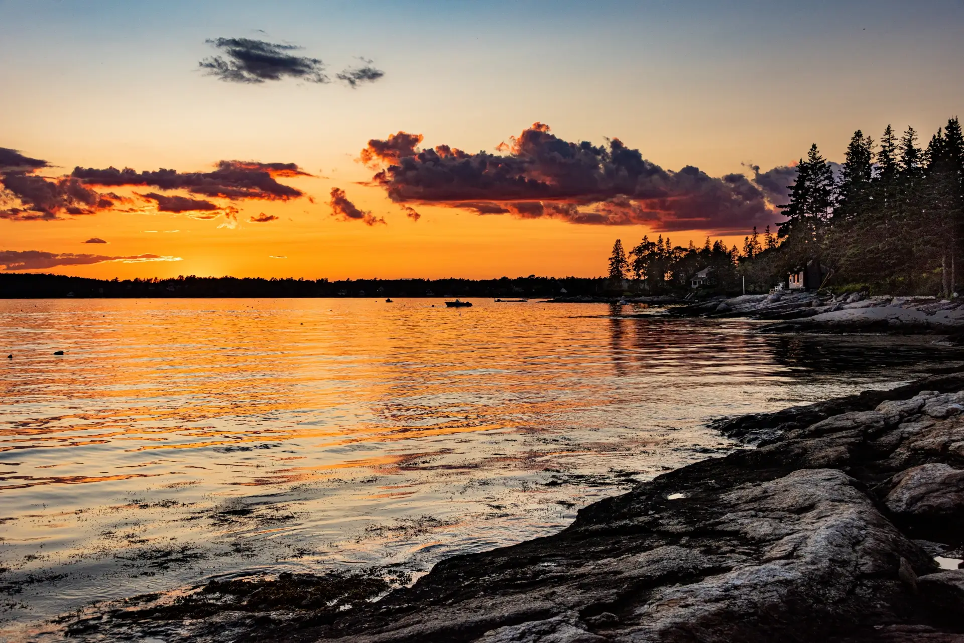 View of sunset over bay on rocky shore of coastal southern Maine