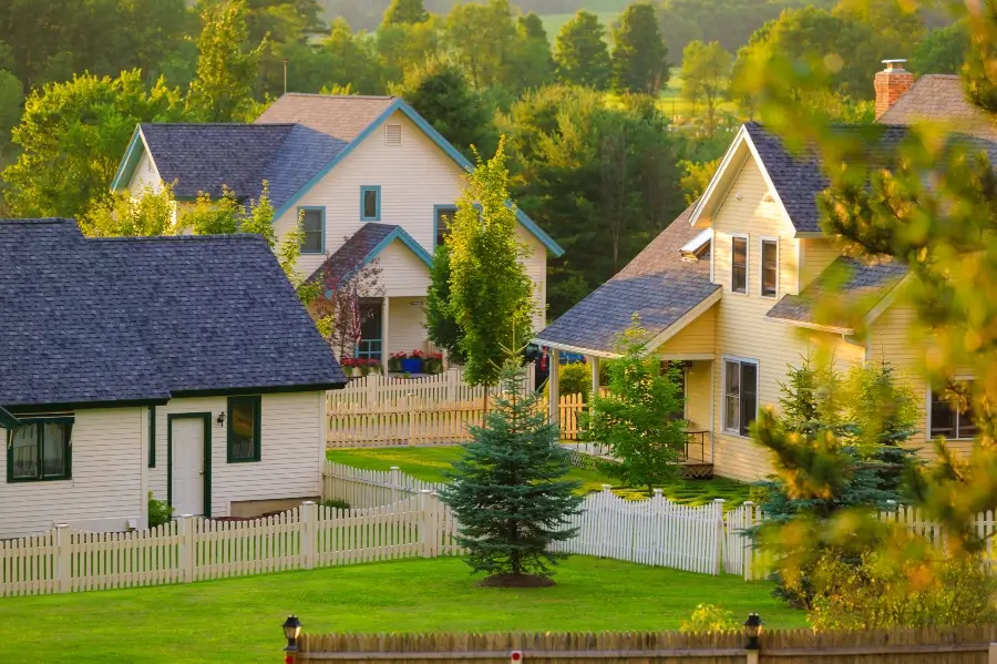 Three rural homes with white picket fences.