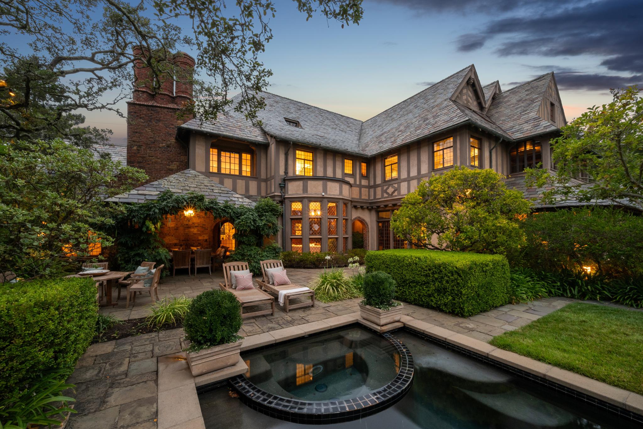 Tudor-style Piedmont home with a landscaped garden and pool at dusk