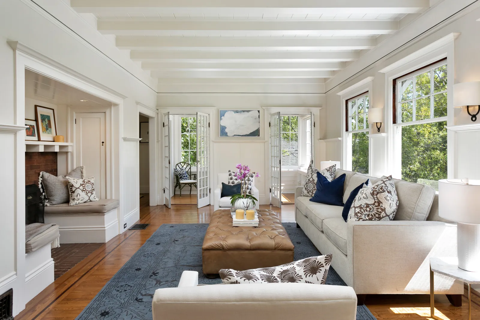 Sunlit craftsman-style living room with a beamed ceiling, hardwood floors, and French doors