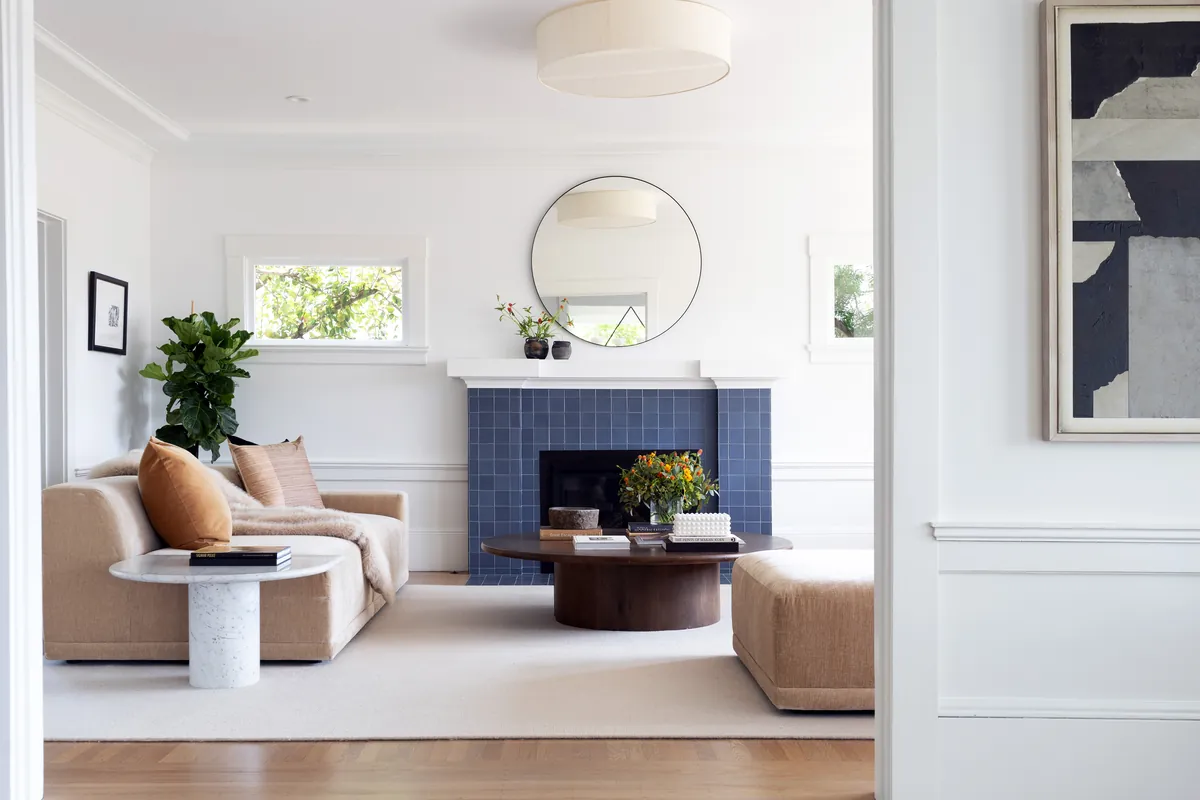 Decluttered, freshly painted living room with a blue-tile fireplace and neutral furniture
