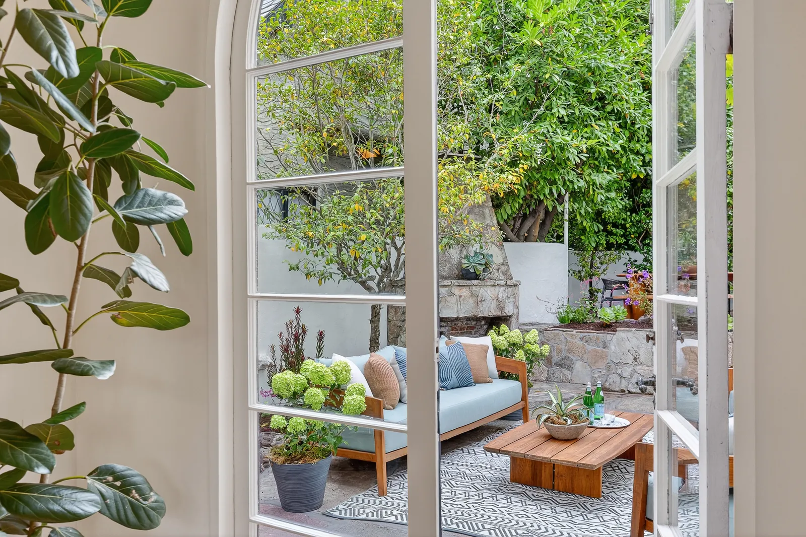 French doors opening from a living room onto a landscaped patio with outdoor seating