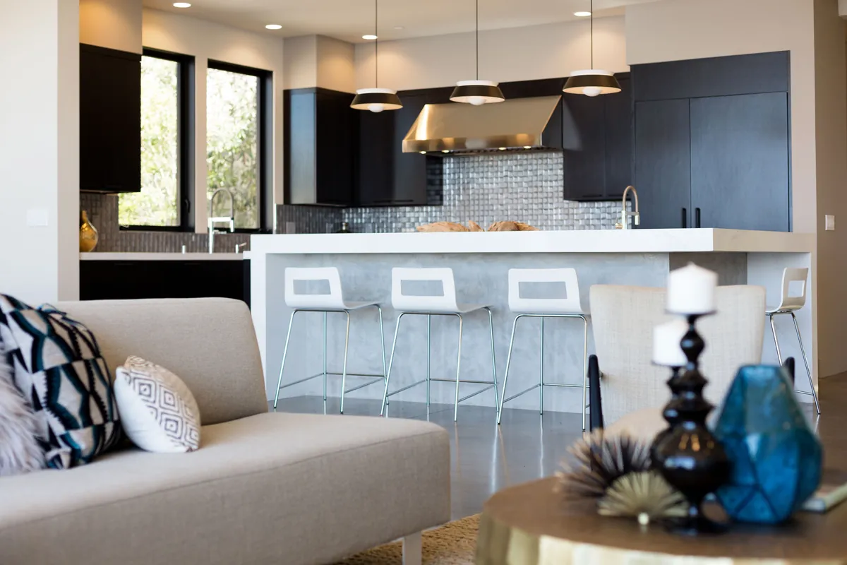 Modern kitchen with dark cabinetry, pendant lights, and a counter with white bar stools