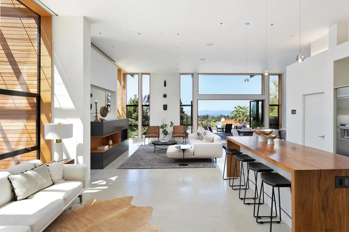 Open-plan living and kitchen space with tall windows and a distant view of the water
