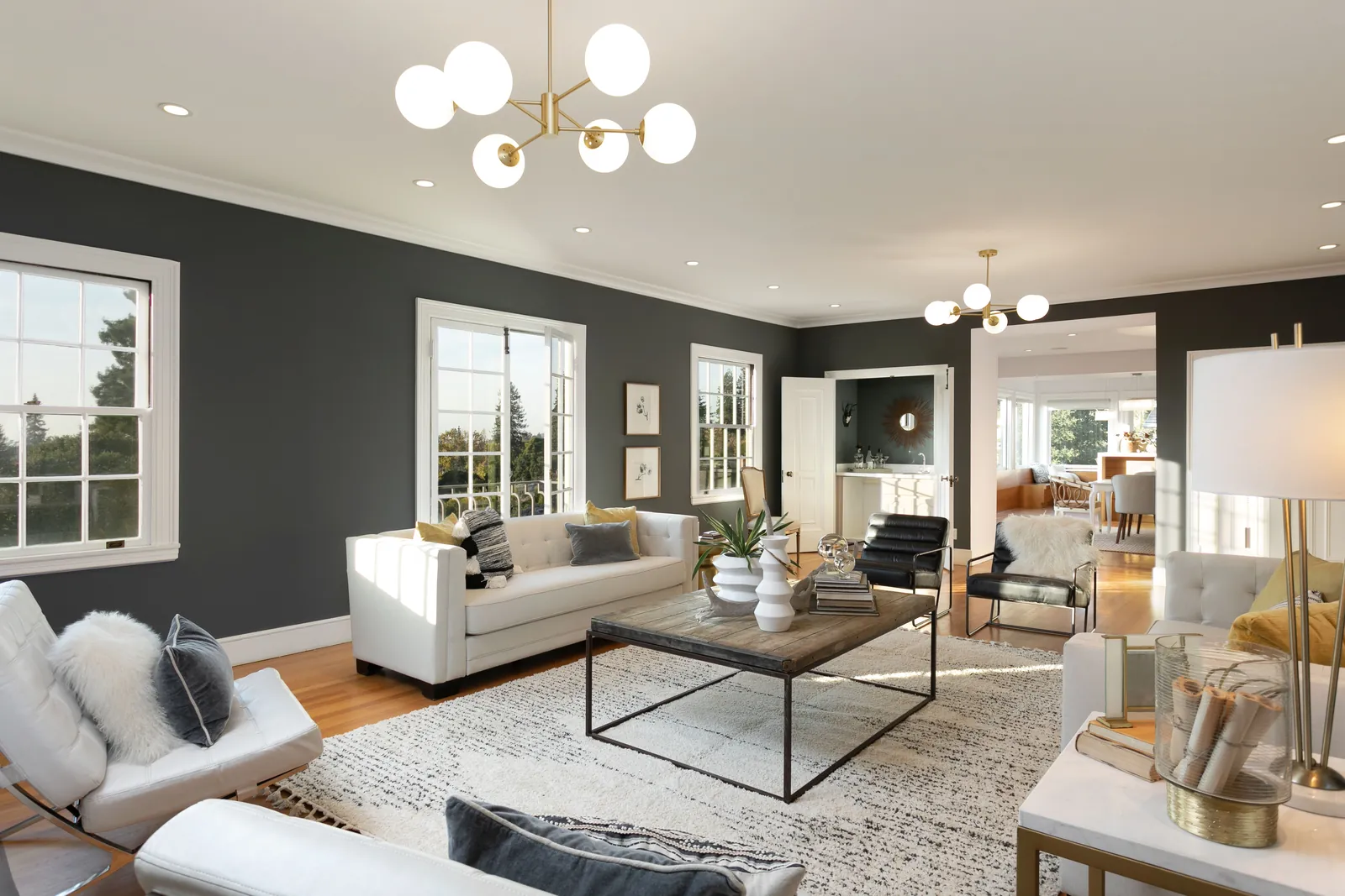 Staged living room with charcoal walls, a white sofa, and a brass globe chandelier