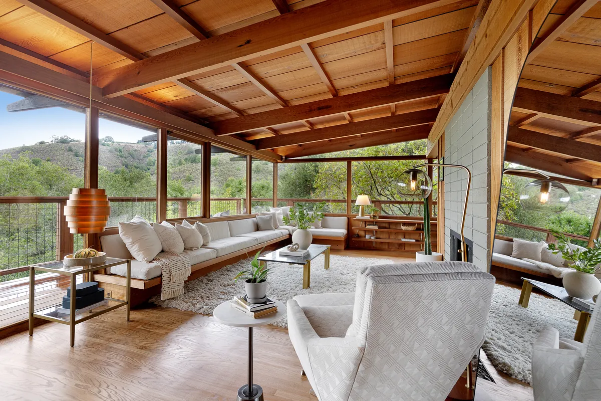 Open sunroom-style living space with exposed wood beams and views across the East Bay hills