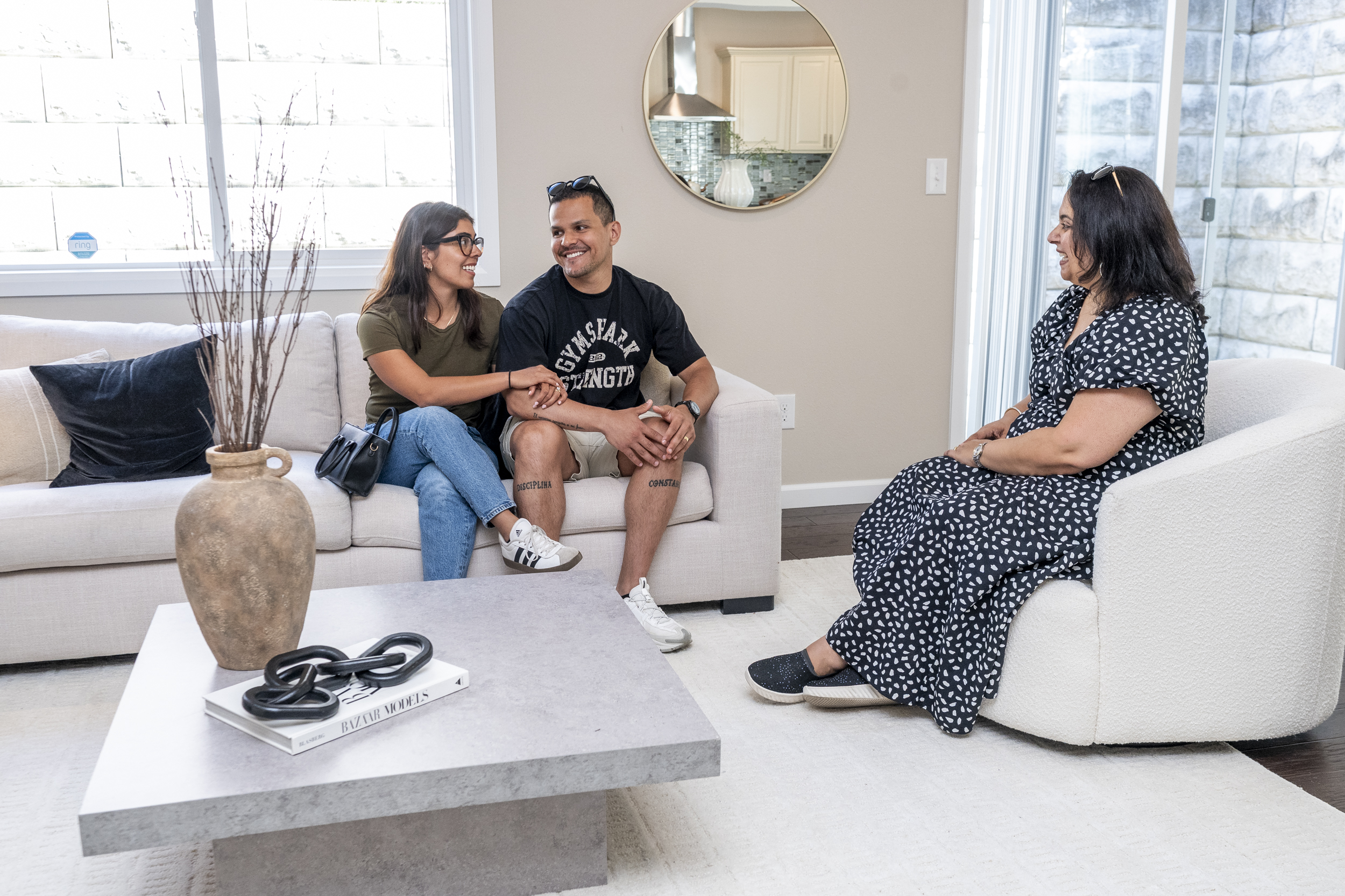Three people talk together in a bright living room.