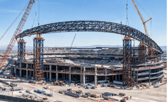 Steel roof-truss arch rising over the under-construction Las Vegas Athletics ballpark on the Strip.