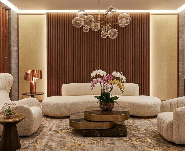 Luxury living room with curved cream sofas, a round marble coffee table, white orchids, and warm ribbed timber wall panelling
