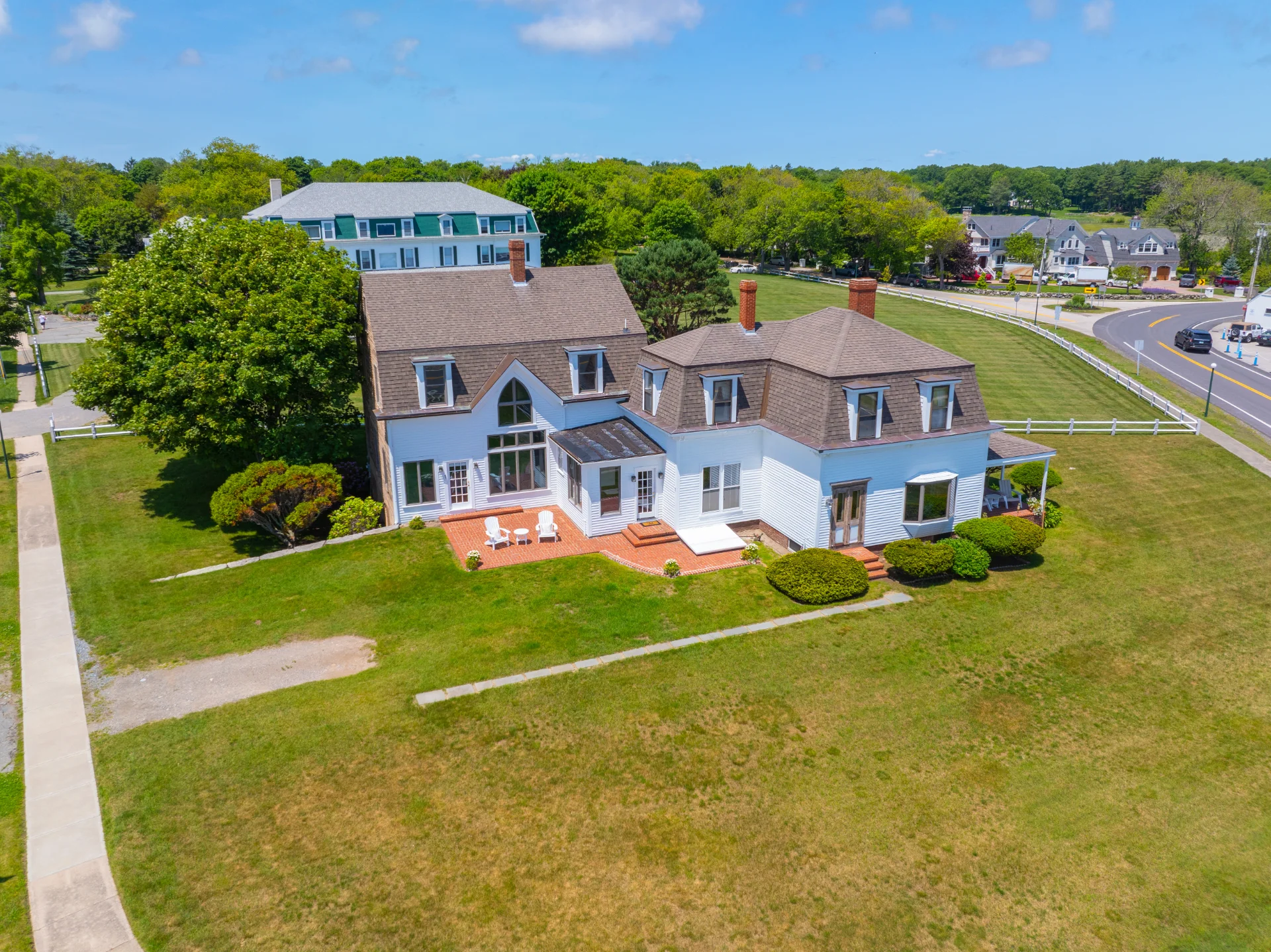 Aerial view of a shingled New England coastal home with a wide lawn