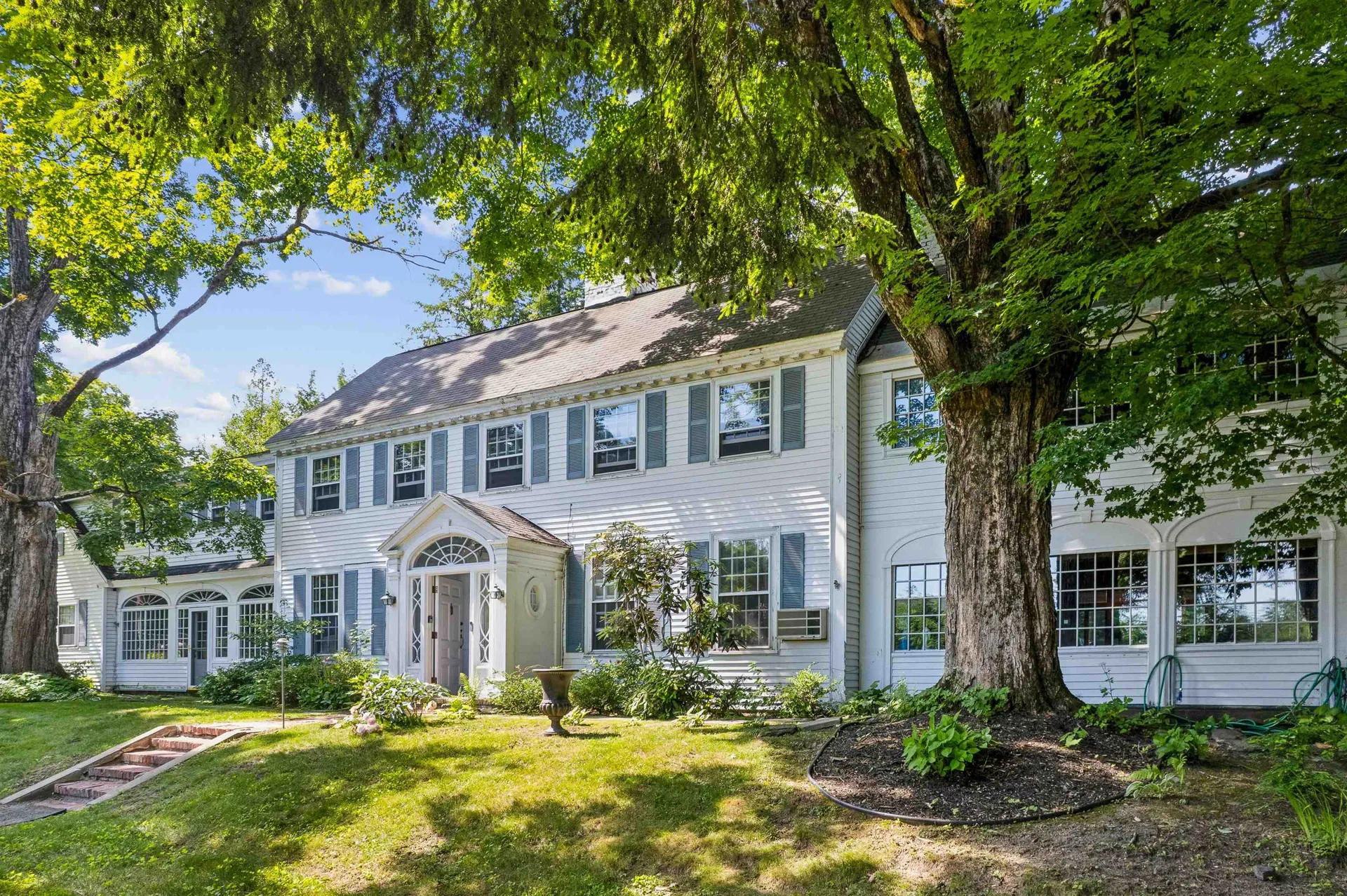 Historic New Hampshire colonial home shaded by a mature tree
