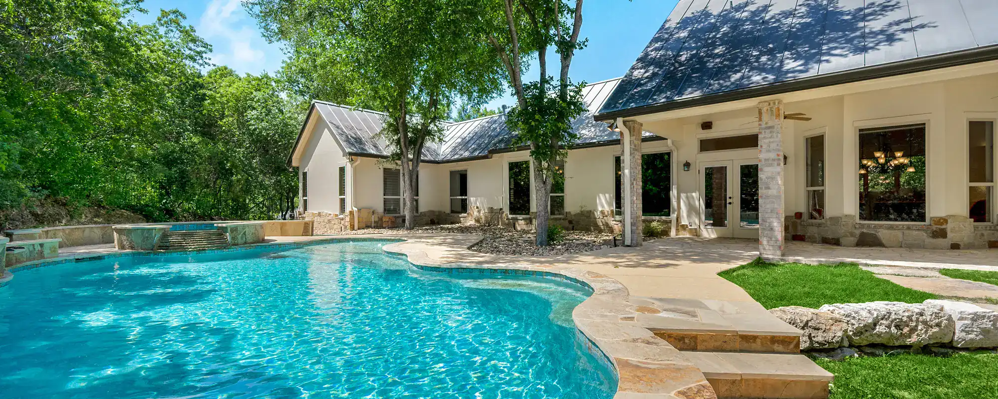 Backyard swimming pool beside a stucco home