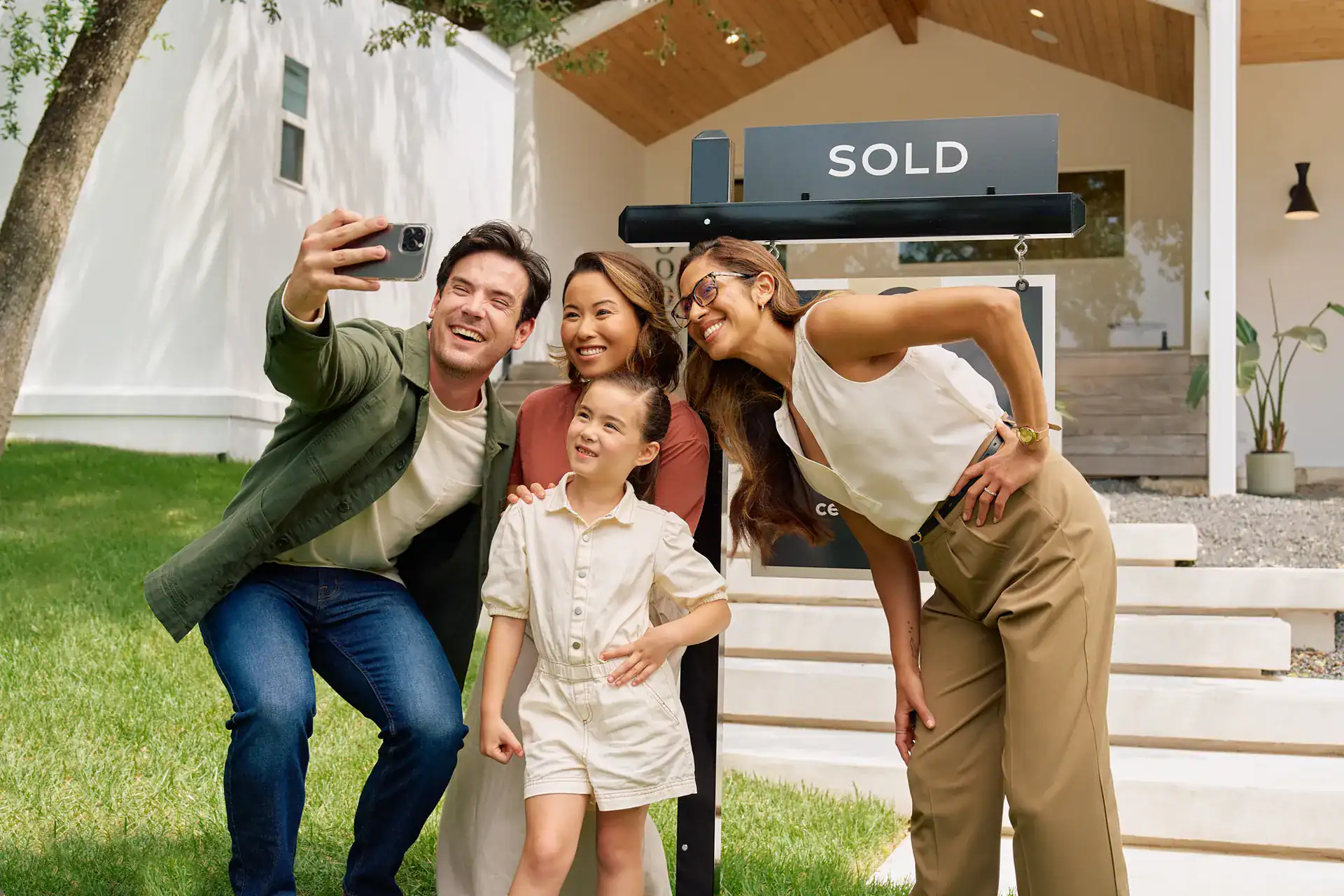 Family taking a selfie with their Century 21 agent beside a SOLD sign