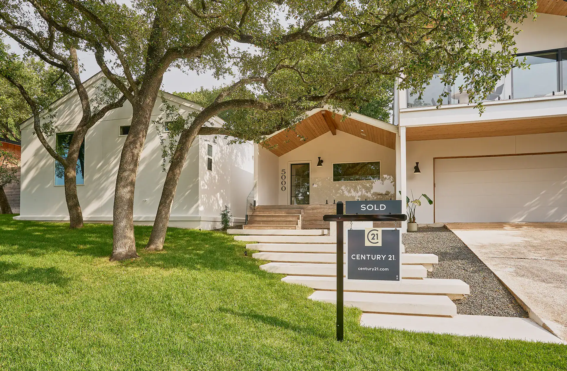 Home on a tree-lined street with a Century 21 SOLD sign