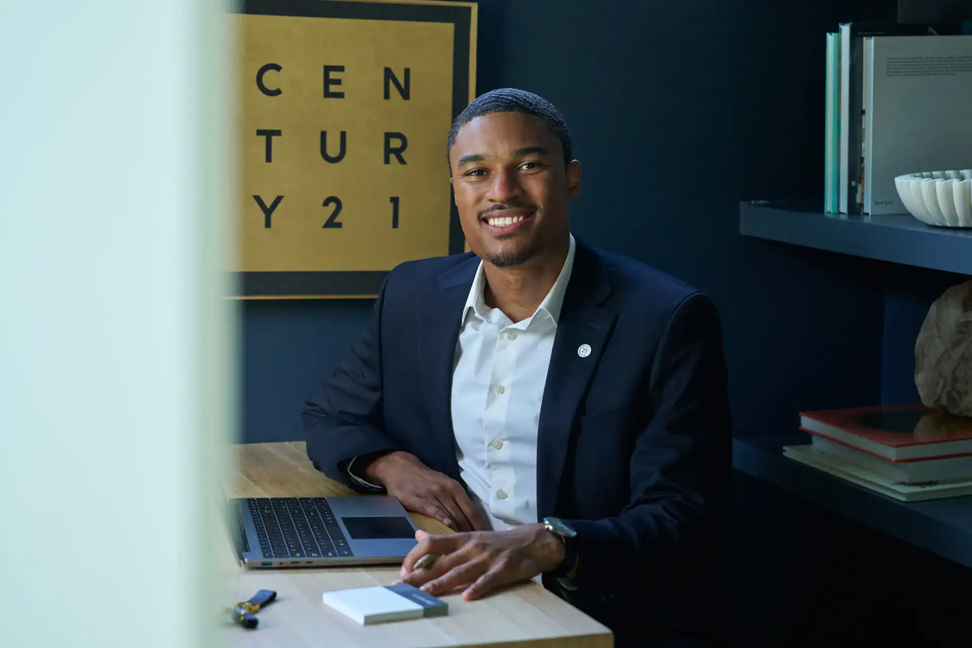 Smiling Century 21 agent at a desk in the office