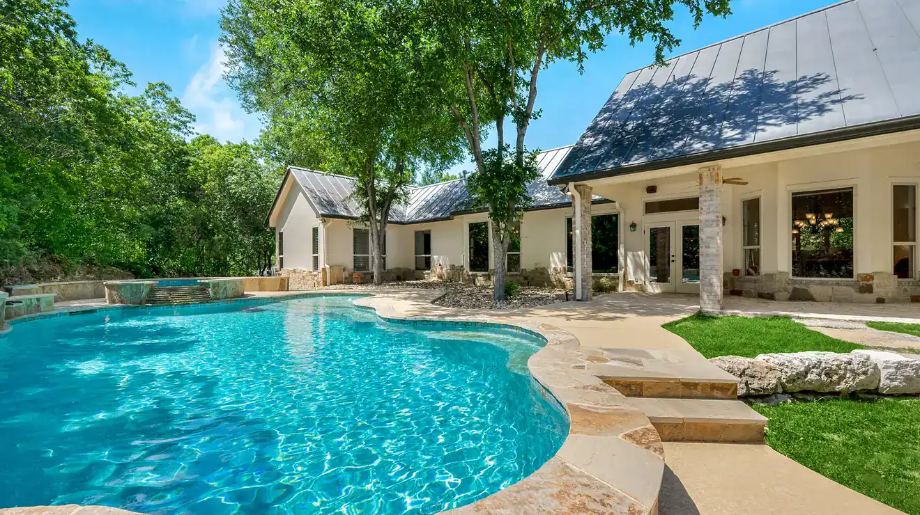 Backyard swimming pool beside a stucco home