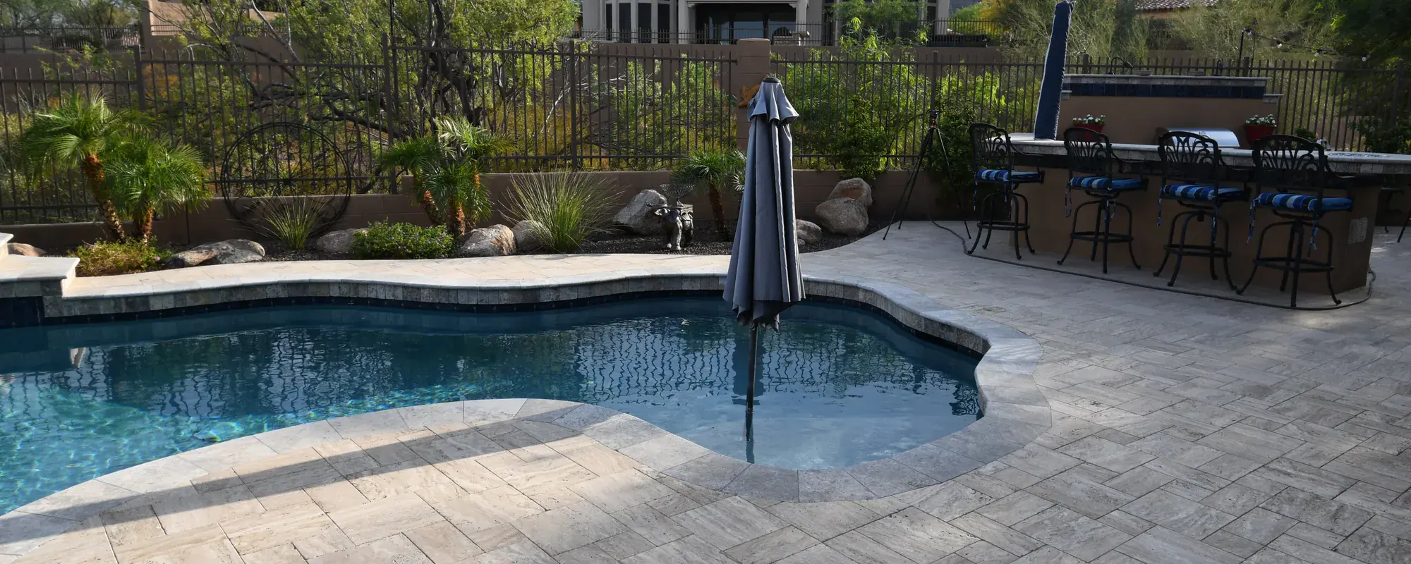 Desert-landscaped backyard with a tiled pool deck