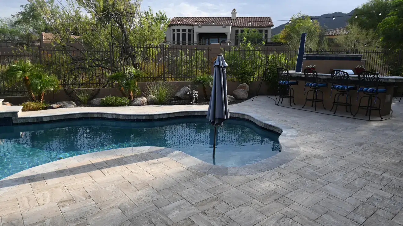 Desert-landscaped backyard with a tiled pool deck