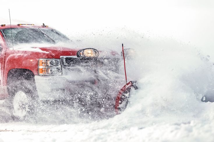 Red pickup truck with a snowplow clearing snow
