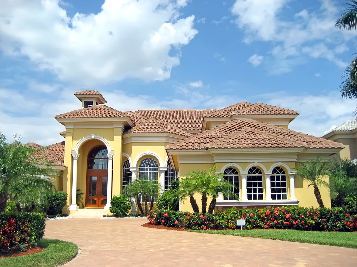 Large pink and yellow tropical house with circular driveway.