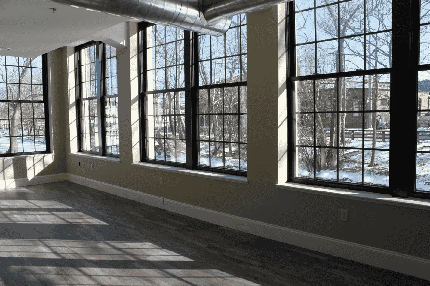 Sunlit loft at the US Rubber Lofts with tall black-framed factory windows and wide-plank floors