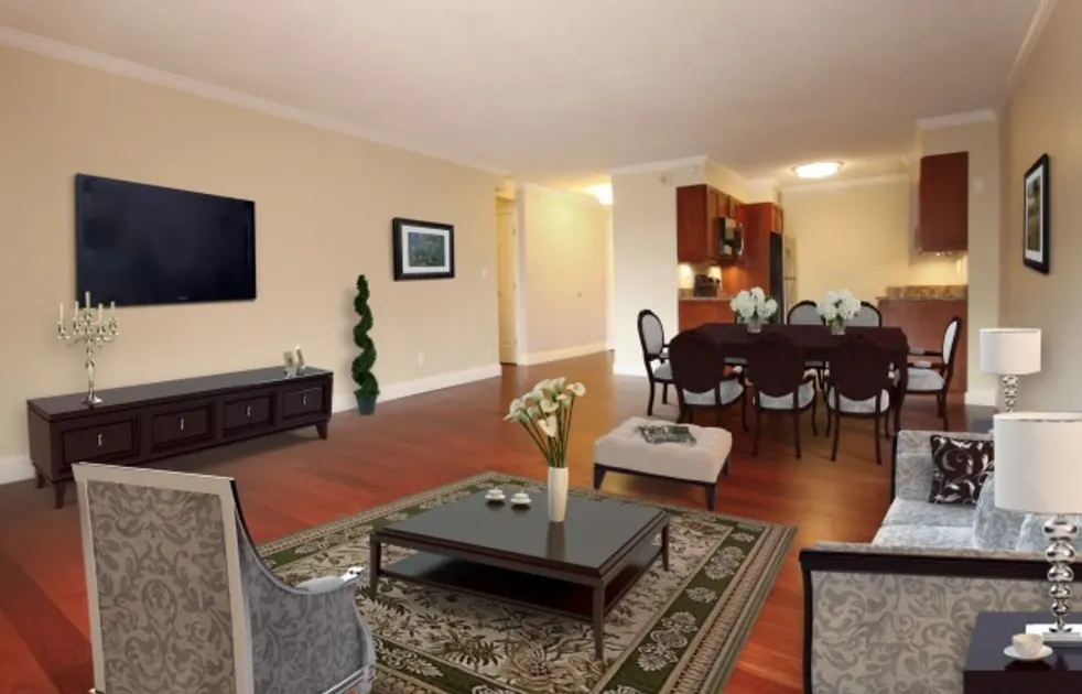 Open living and dining room at Regency Plaza with hardwood floors and a wall-mounted TV