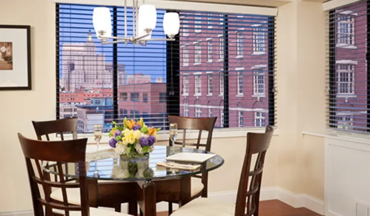 Dining area at Regency Plaza in Providence with a round table and downtown views through tall windows