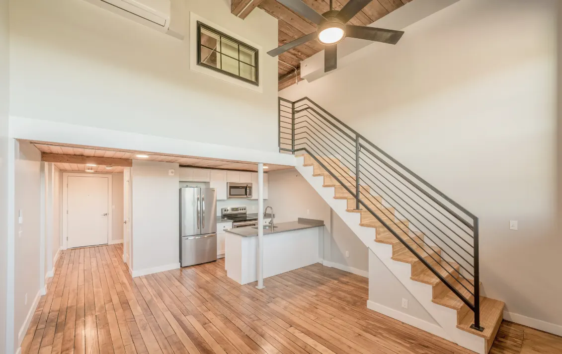 Two-story loft at Strive Lofts in Providence with a steel-railed staircase, wood floors and an open kitchen