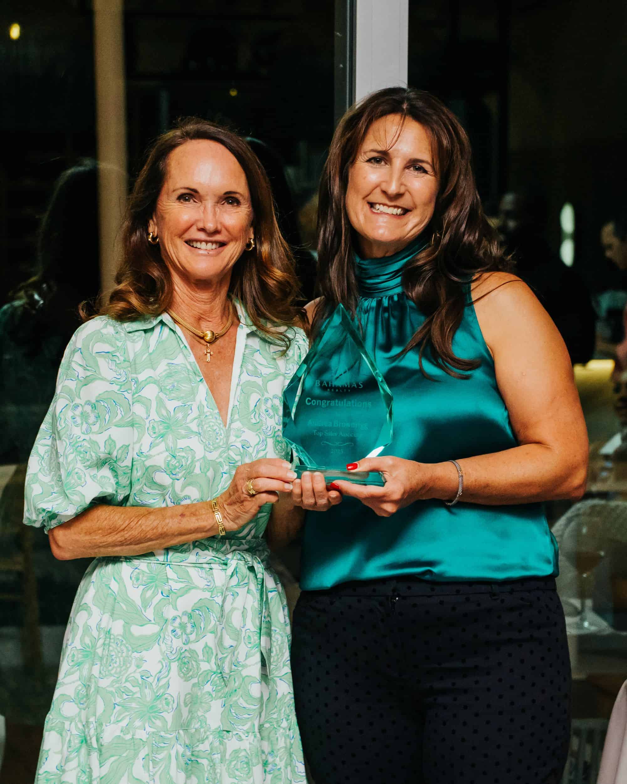 two women holding an award smiling