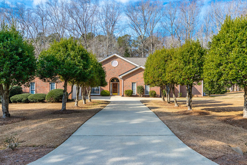 front view of brick house from driveway with trees lining