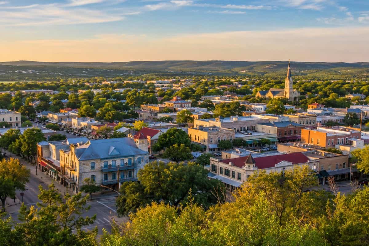 Aerial view of a Texas Hill Country downtown with commercial buildings and rolling hills at sunset