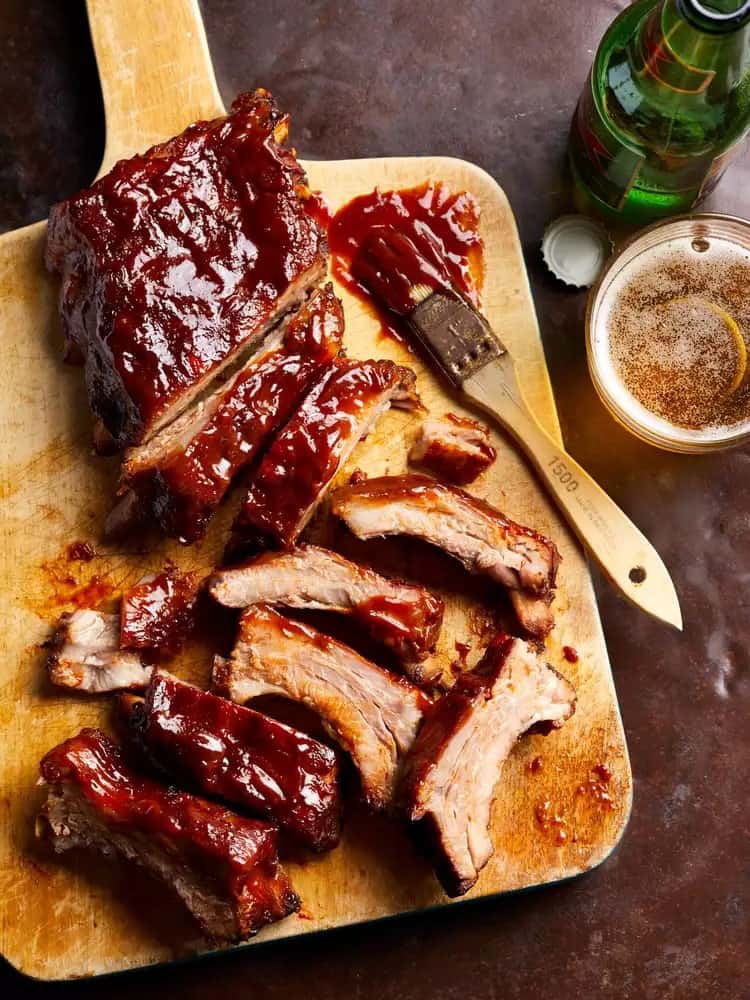 tangy molasses barbeque ribs partially cut on a wooden board