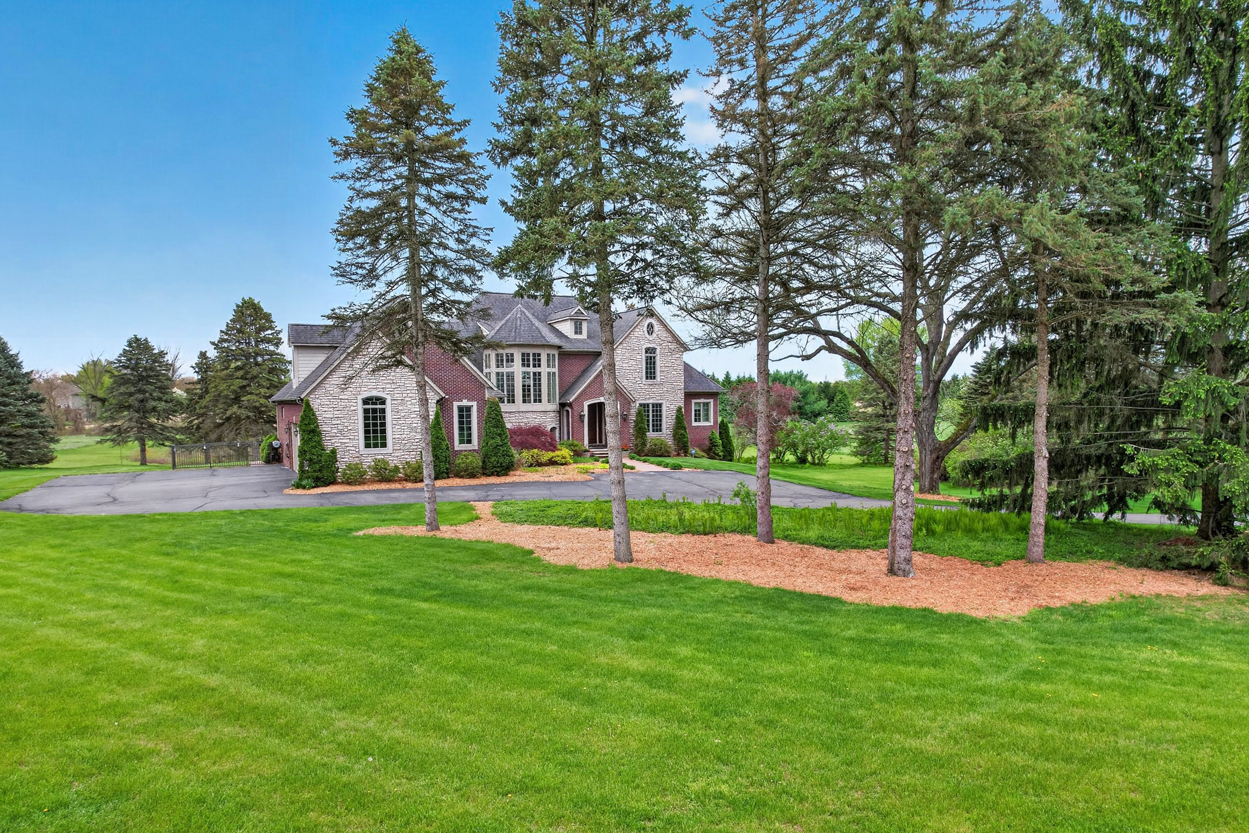 Twilight exterior view of 60675 Pontiac Trail, a custom 12.87-acre estate in New Hudson, Michigan