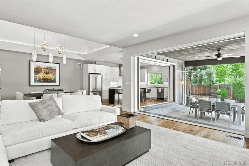 Livingroom with white furniture with a modern kitchen in the background and walkout out patio at 2980 S Cherry Way, Denver