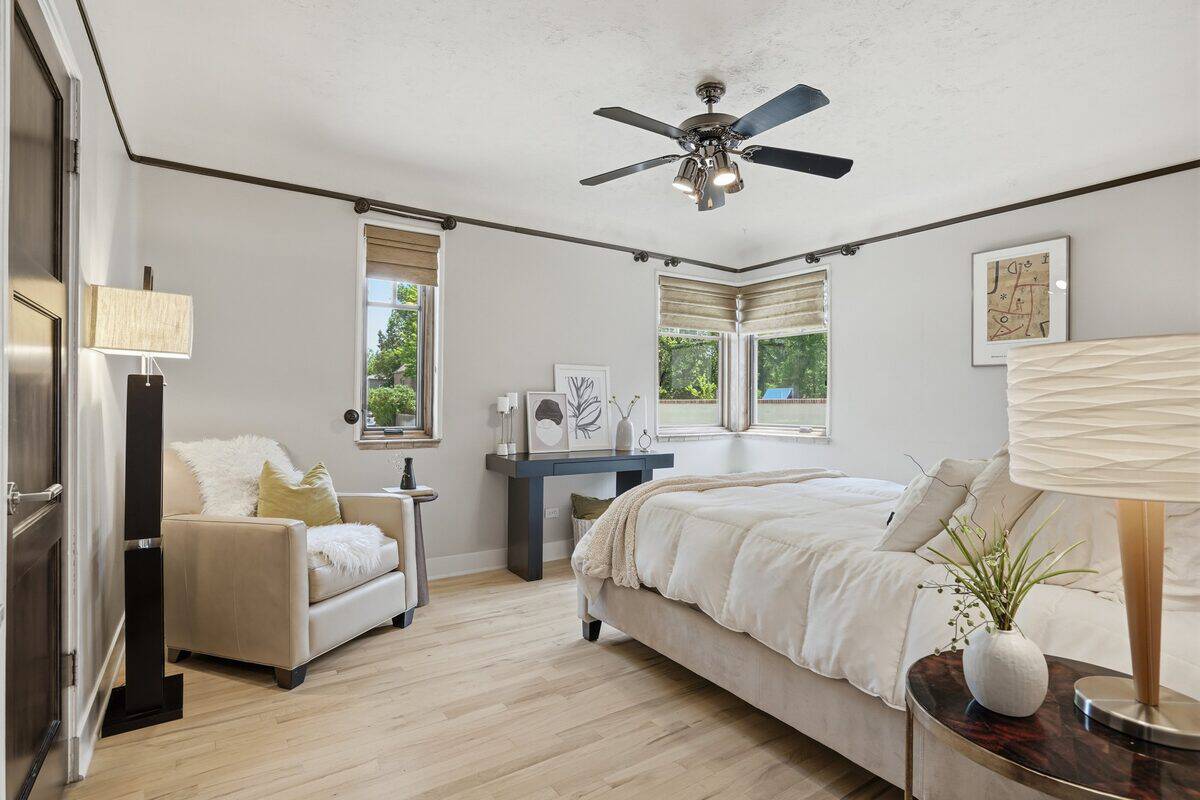 Bedroom with light gray walls, a tan armchair, and a console table after staging, Denver