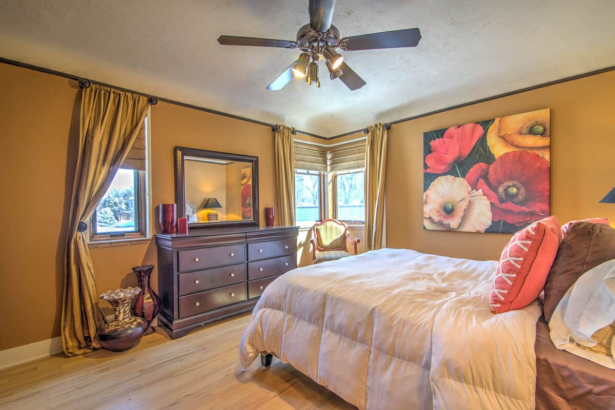 Bedroom with gold walls, a large poppy painting, and a dresser before staging, Denver