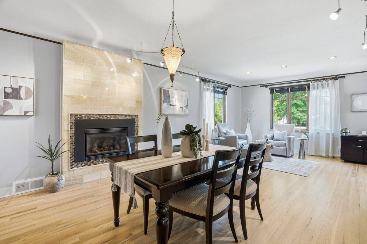 Dining table with four chairs by a tiled fireplace, open to a bright sitting area after staging, Denver