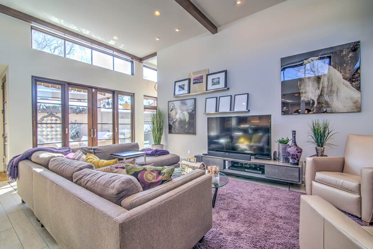 Great room with a sectional, purple rug, and tall windows before staging, Denver