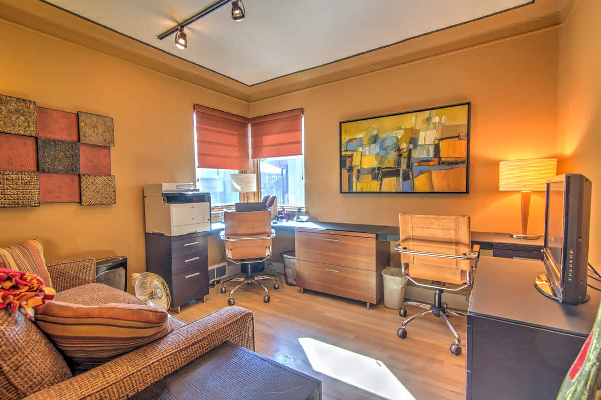 Home office with orange walls, a printer, and a sofa by an L-shaped desk before staging, Denver