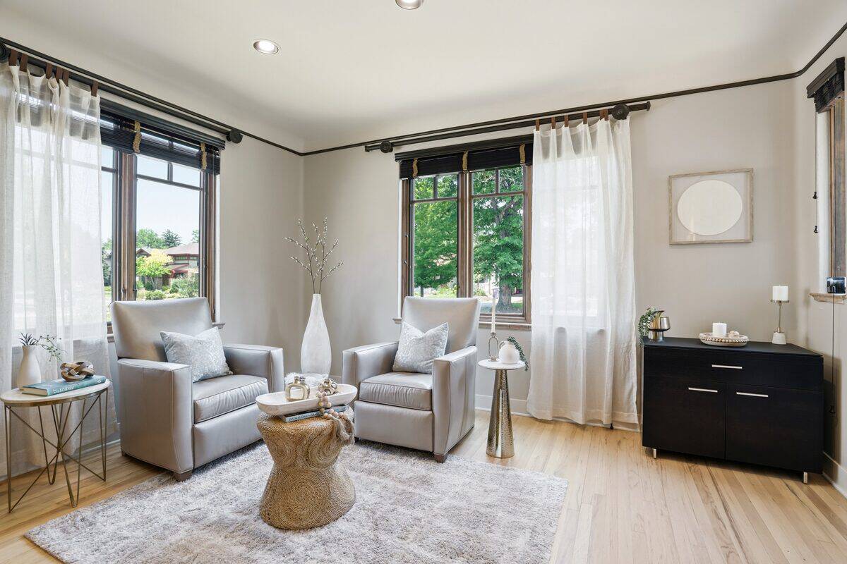 Front living room with two gray leather armchairs, sheer curtains, and light walls after staging, Denver