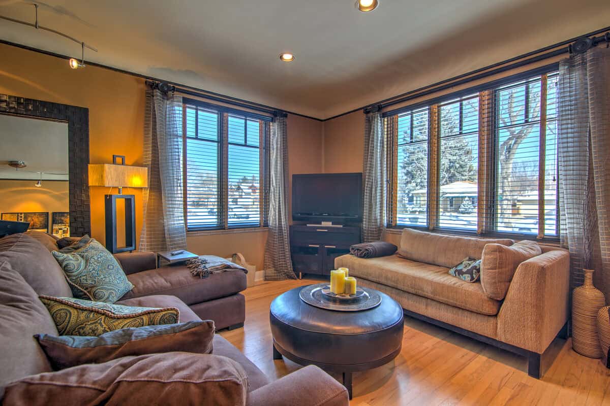 Gold-walled living room with heavy sofas and a leather ottoman before staging, Denver